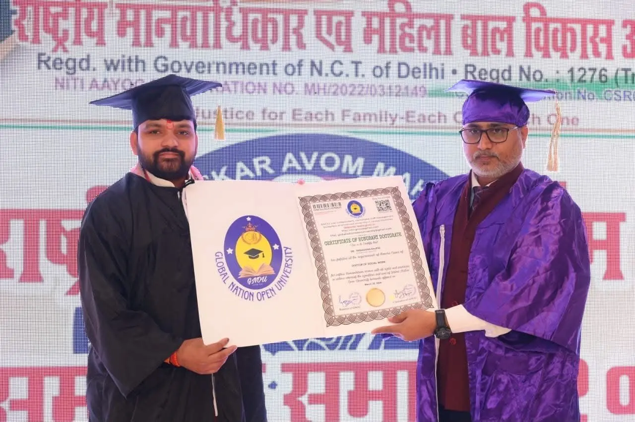 Acharya Tribhuvan Ji in a graduation gown receiving the honorary doctorate certificate on stage