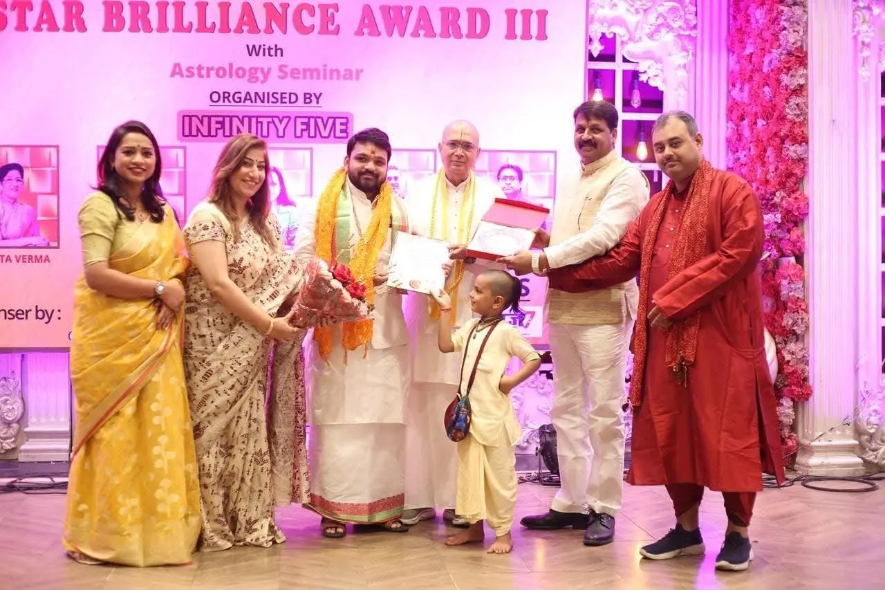 Acharya Tribhuvan Ji on stage at the Star Brilliance Award III with the organisers, holding his certificate